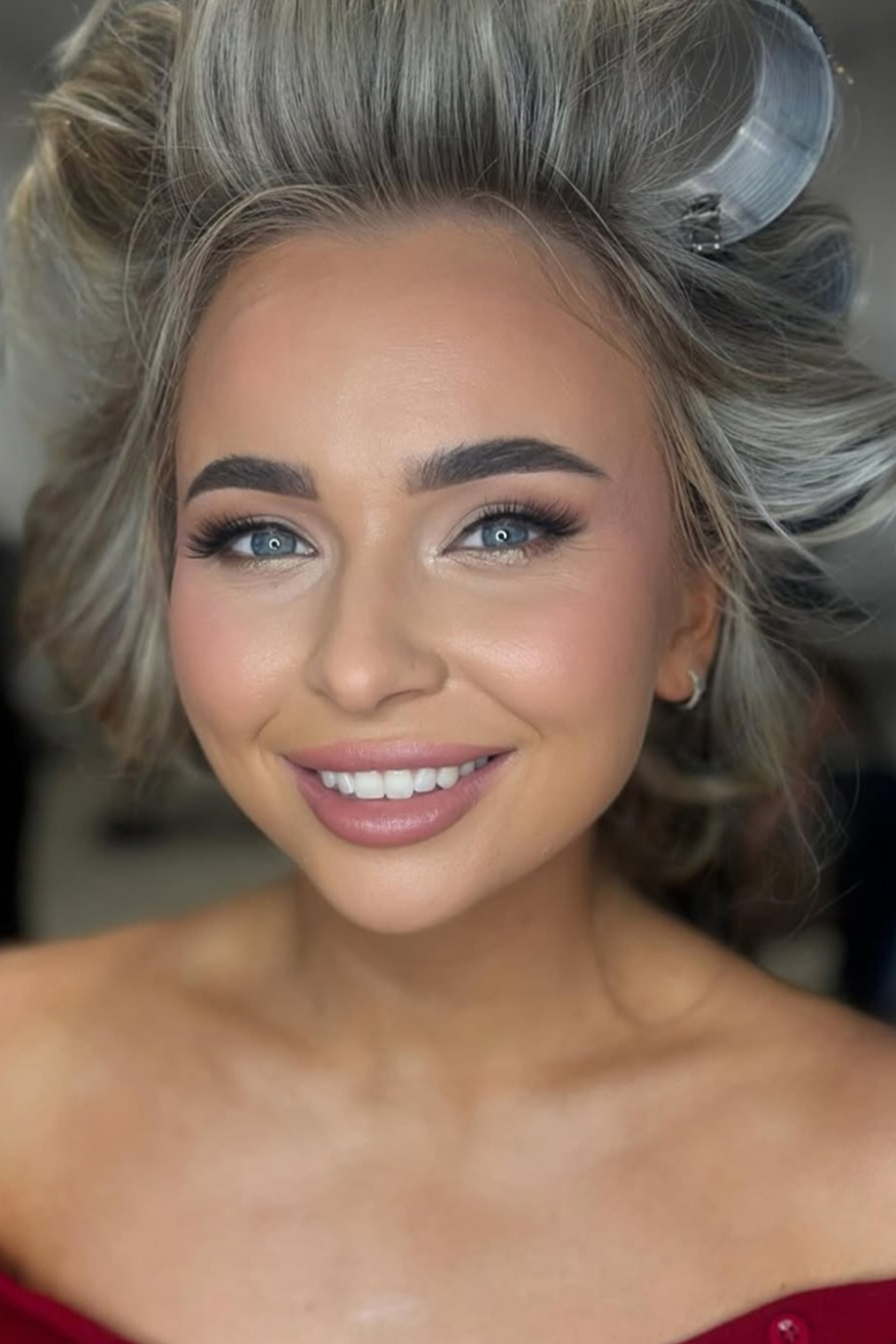 Girl with rollers in hair smiling with soft glam makeup